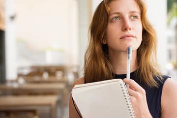 woman holding a notebook and thinking